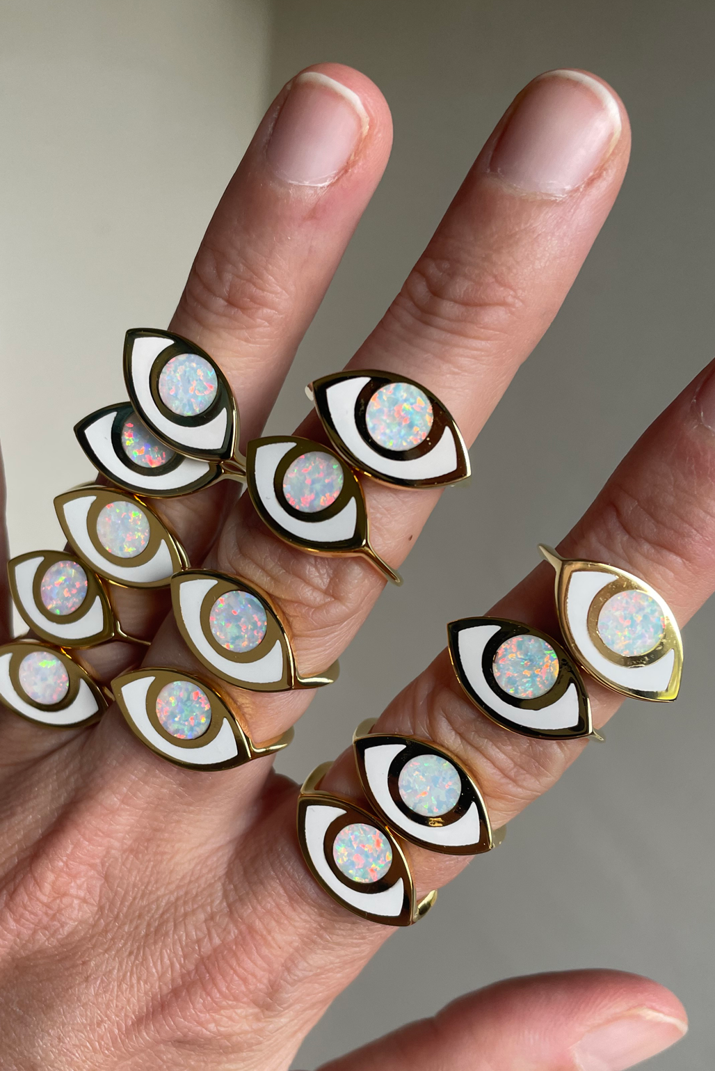 a hand wearing multiple jelly opal opal gold third eye rings