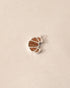 A silver charm in the shape of a croissant with flaky jasper inlaid into its design, displayed against a neutral background.