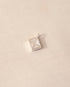 A silver envelope-shaped charm with mother of pearl inlay placed on a beige background