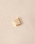 A  gold vermeil envelope charm with mother of pearl inlay on a beige background