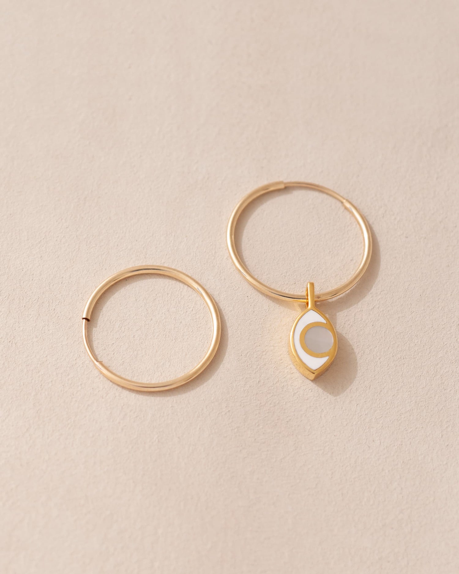 gold hoops with a gold eye charm inlaid with mother of pearl