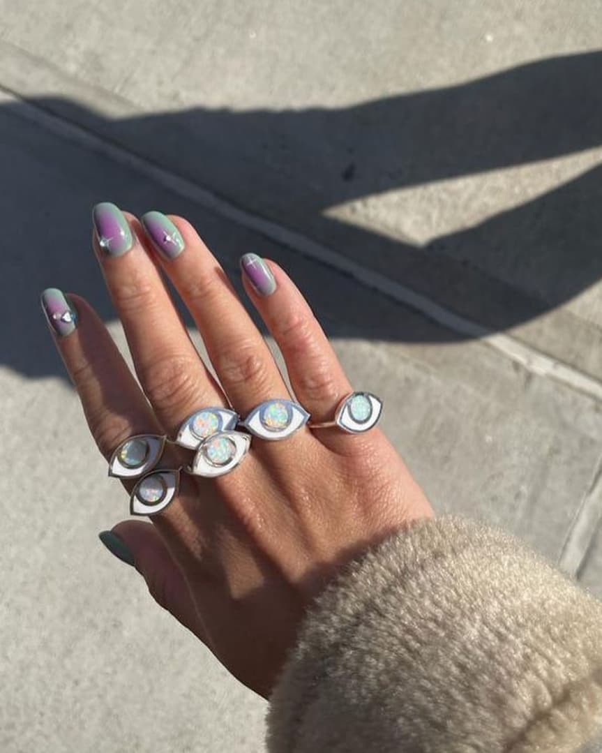 a hand wearing 6 opal silver eye rings