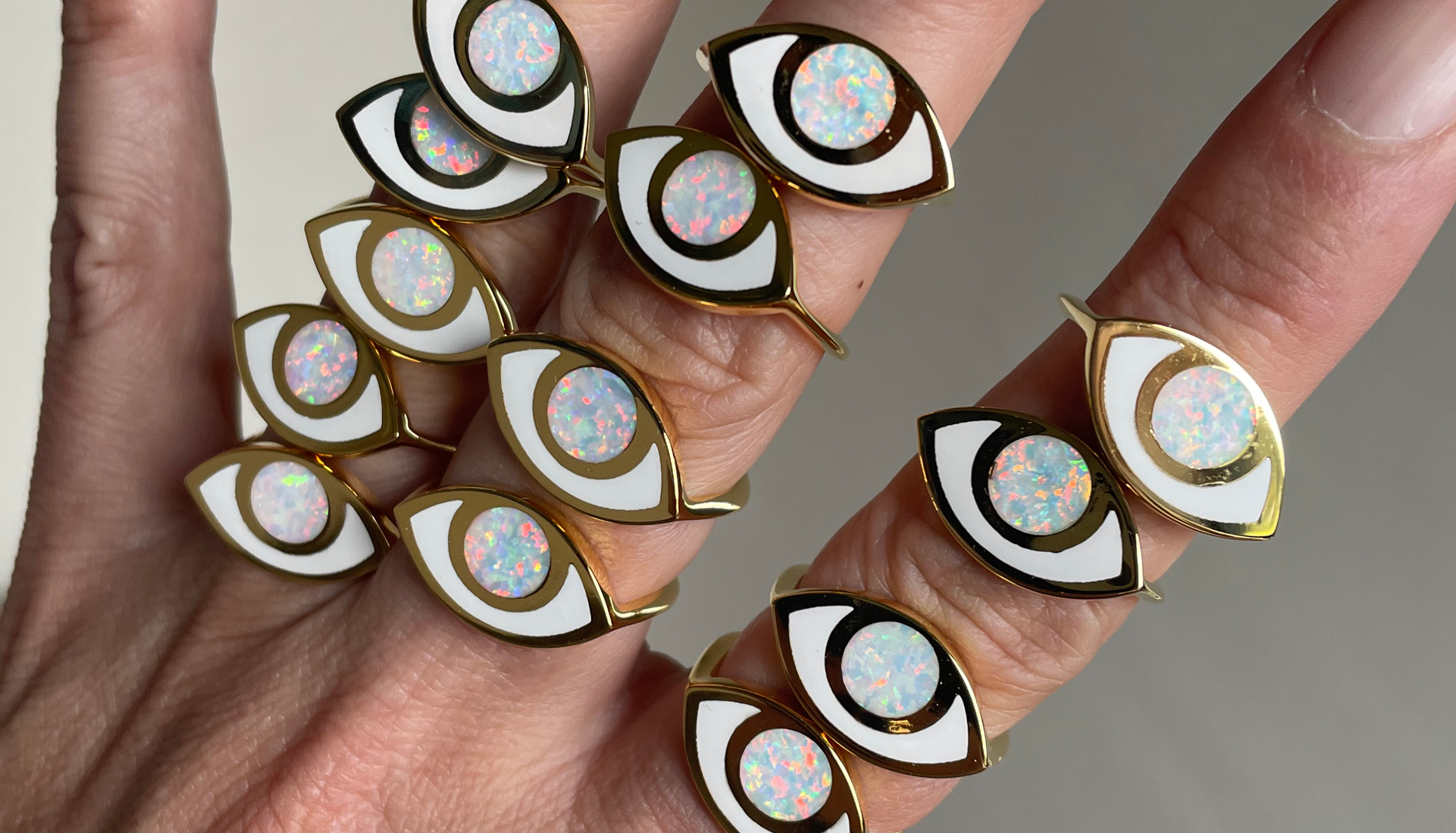 a hand wearing multiple jelly opal opal gold third eye rings