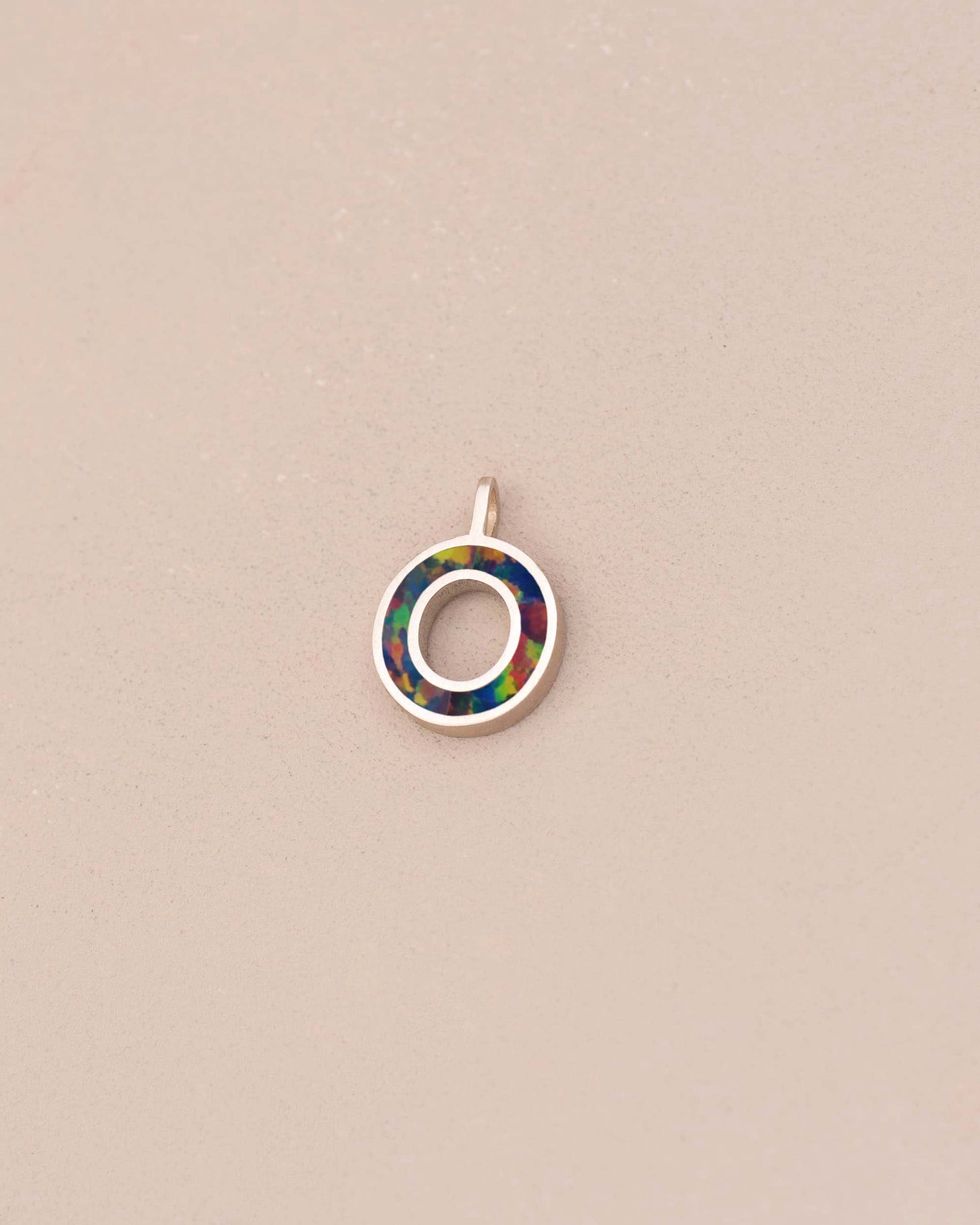 Small circular pendant with multicolored inset on a beige background