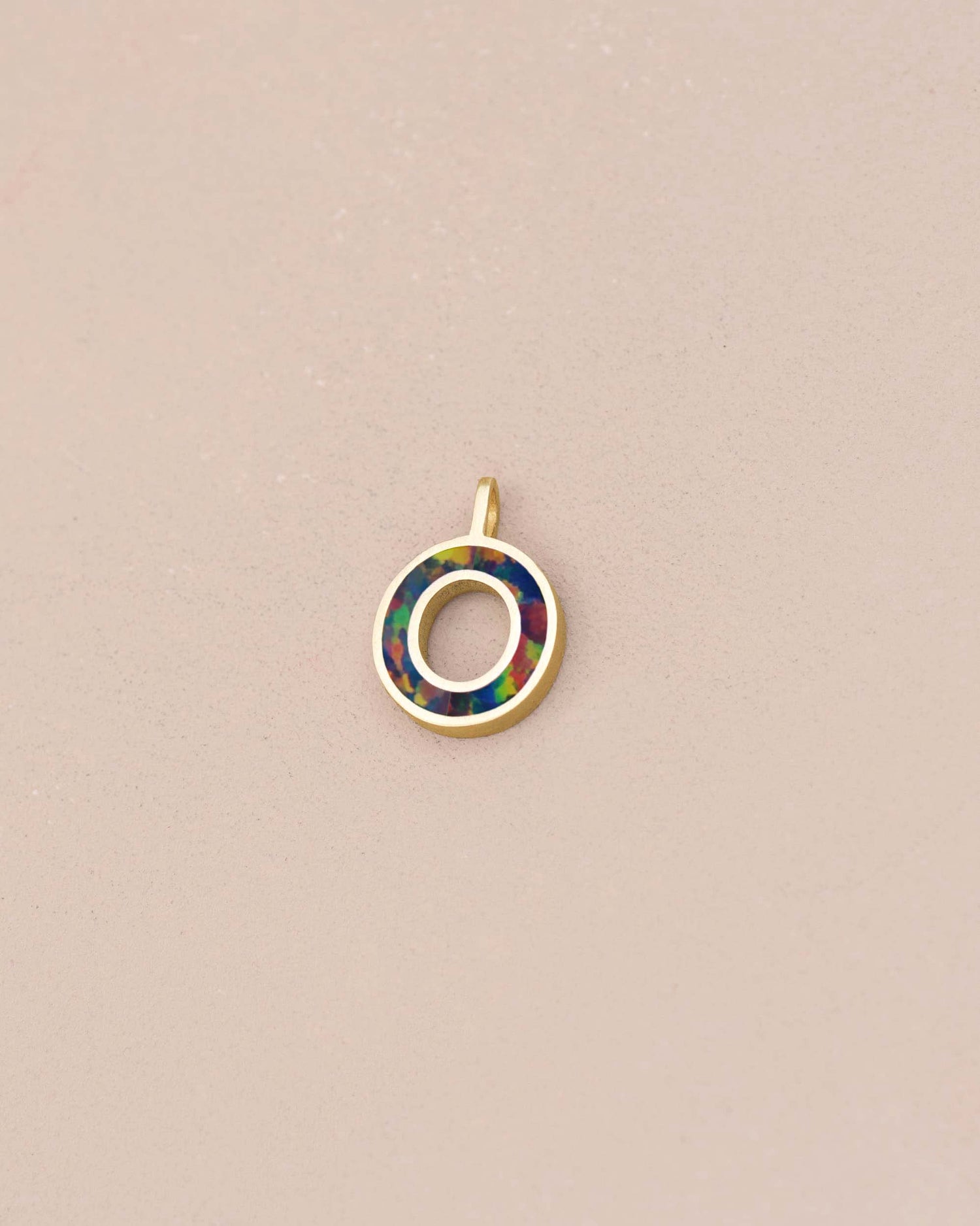 Jewelry pendant with multicolored circle design on a beige background