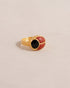 A gold ring featuring a scarab design with onyx and red jasper inlays, displayed against a neutral background.
