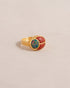 A gold ring featuring a scarab design with starry opal and red jasper inlays, displayed against a neutral background.
