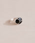 A silver ring featuring a central onyx stone flanked by onyx stones on either side, set against a neutral background.