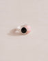 A silver ring with a pink opal center and surrounding onyx, placed on a plain background.