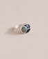 A silver ring featuring a central opal stone flanked by onyx stones on either side, set against a neutral background.