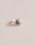 A silver ring featuring a central opal stone flanked by pink opal stones on either side, set against a neutral background.