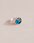 A silver ring featuring a central turquoise stone flanked by onyx stones on either side, set against a neutral background.