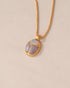 A gold vermeil necklace featuring a scarab amulet pendant with inlays of purple and white stones, displayed against a neutral background.