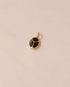 A gold charm featuring a scarab design with onyx inlays, displayed against a neutral background.