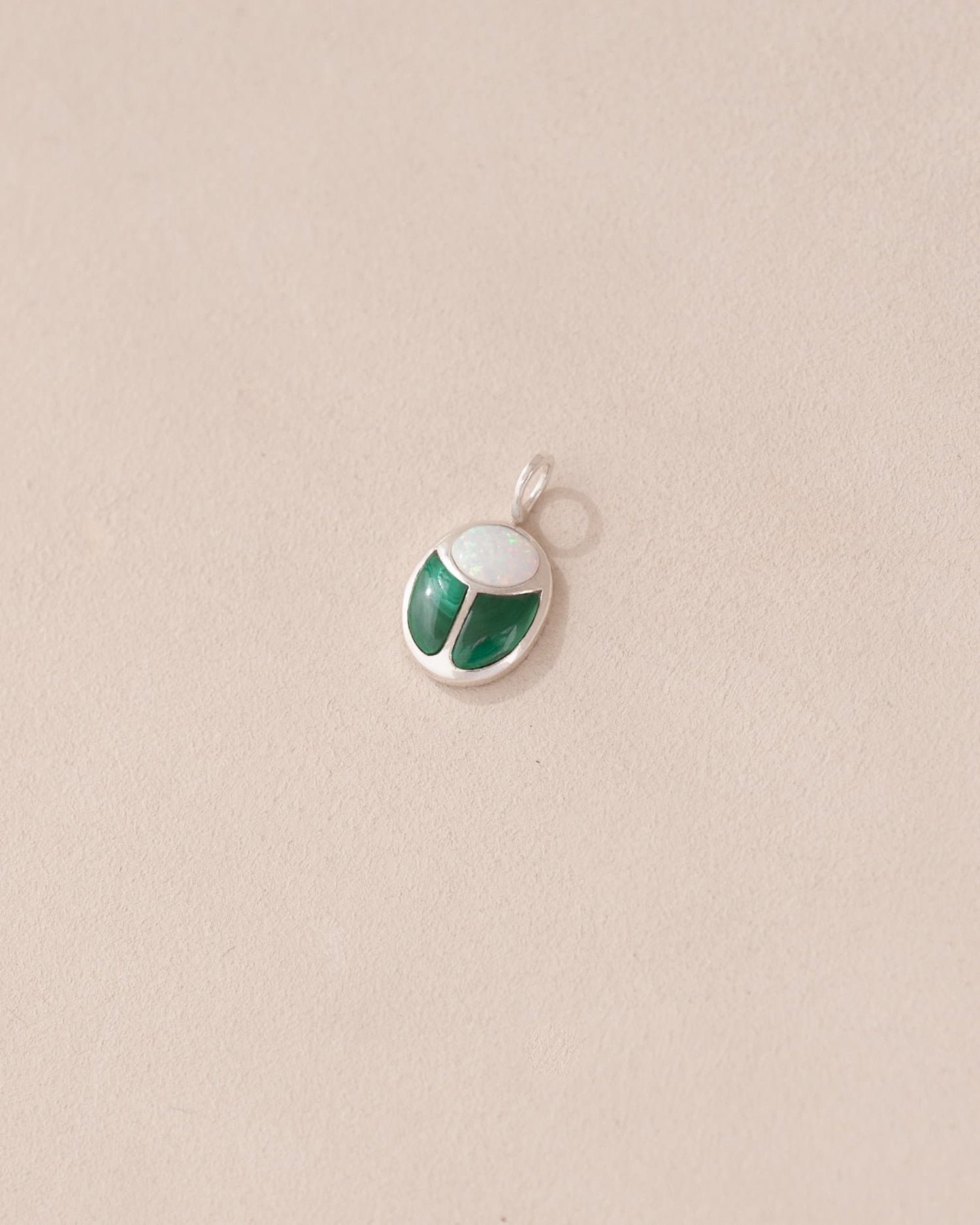 A silver charm featuring a miniature scarab amulet design with jelly opal and malachite inlay, displayed against a neutral background.
