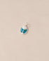A small silver charm featuring a blue and white stone, designed to resemble a scarab amulet.