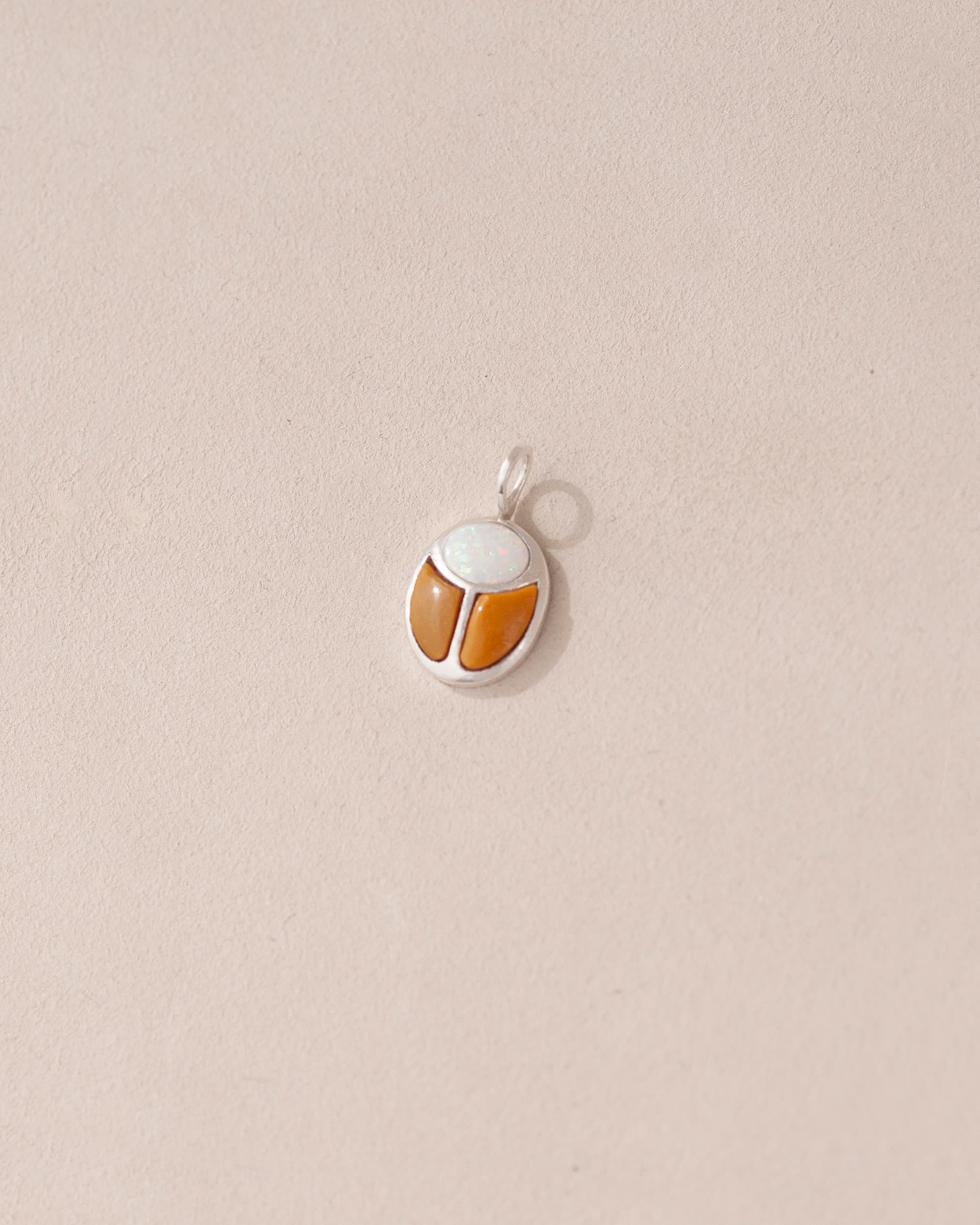 A silver charm featuring a scarab design with jelly opal and mookaite stones on a light background.