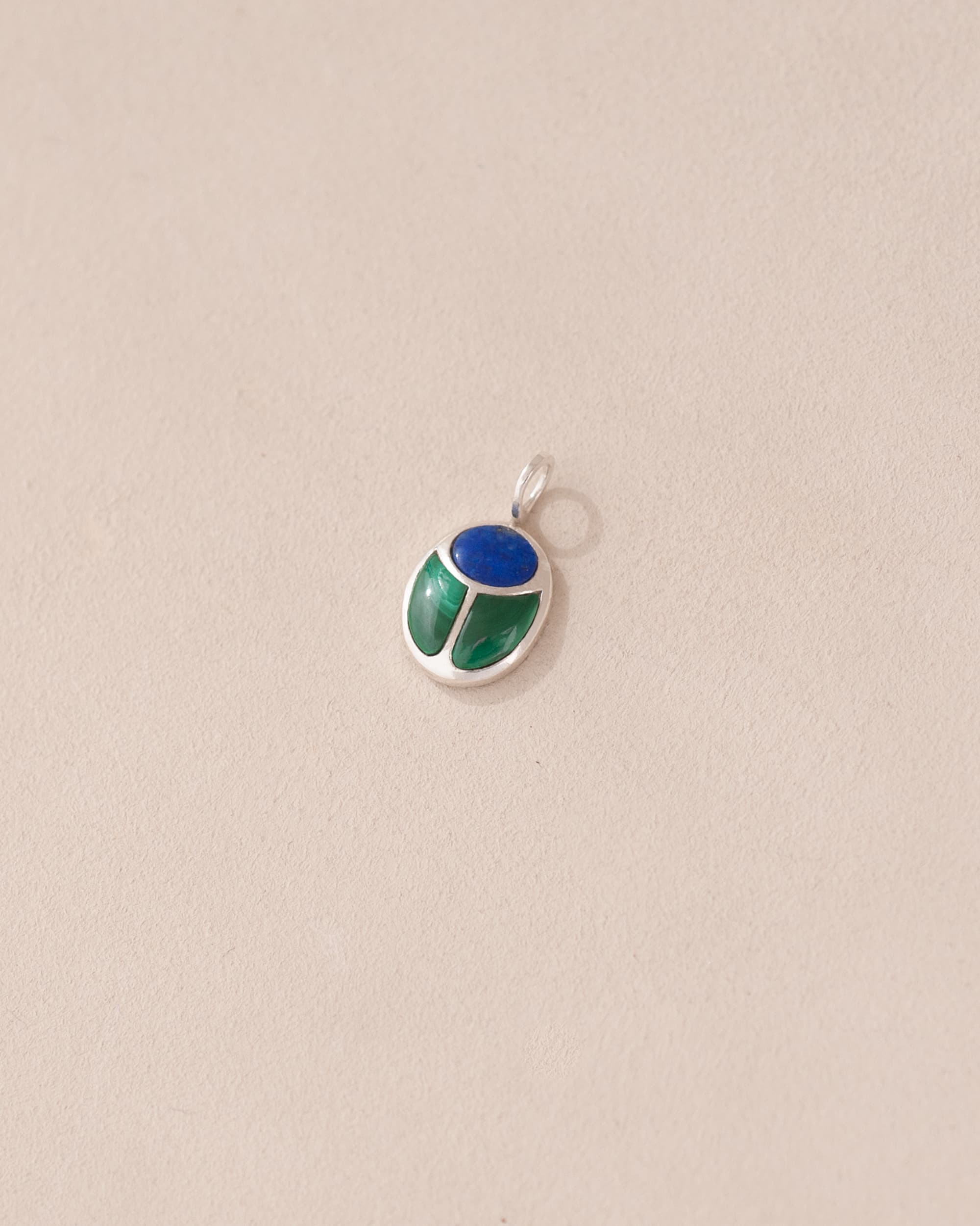 A silver-colored charm with a round lapis lazuli and a teardrop-shaped malachite, attached to a small silver ring.