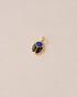 A gold charm featuring a scarab design with lapis lazuli and onyx inlays, displayed against a neutral background.