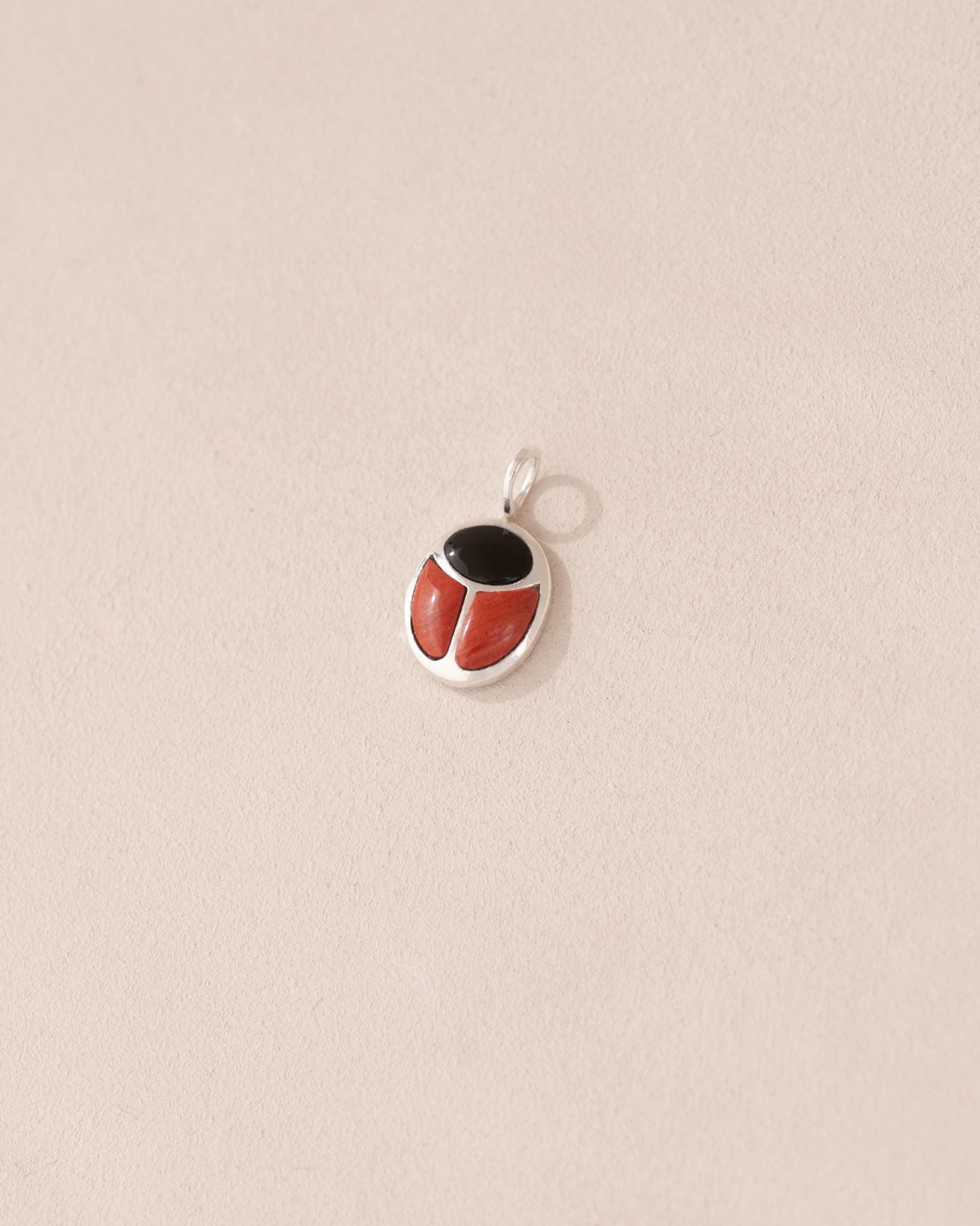 A silver-colored charm with an onyx and red jasper design, intended for use as a talisman.