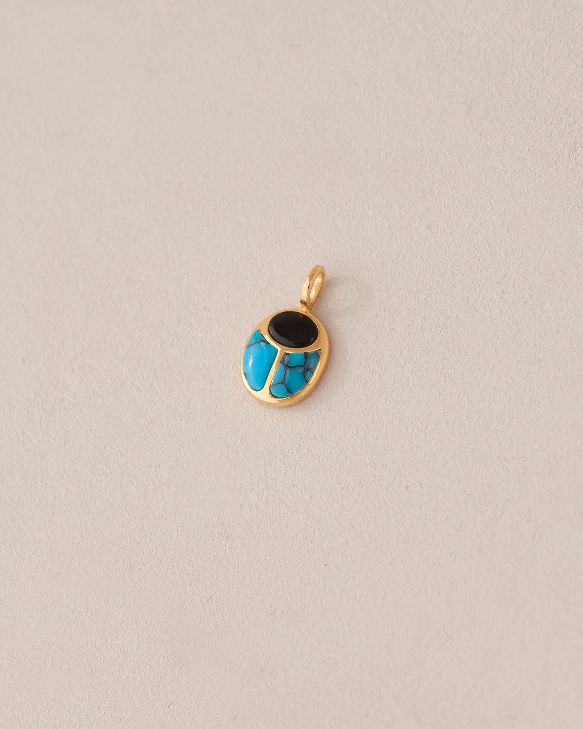 A 14K yellow gold charm featuring a scarab design with onyx and turquoise inlay, displayed against a neutral background.