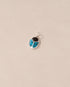 A small silver charm featuring a scarab design with onyx and turquoise inlays, displayed against a neutral background.
