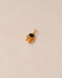 A gold charm featuring a scarab design with onyx and yellow opal inlays, displayed against a neutral background.