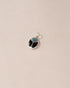 A small silver charm featuring a starry opal and onyx design, shaped like a scarab amulet.