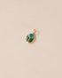 A small turquoise and malachite stone charm in a gold setting, shaped like a scarab, displayed against a light background.
