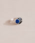 A gold ring featuring a central lapis lazuli stone flanked by onyx stones on either side, set against a neutral background.