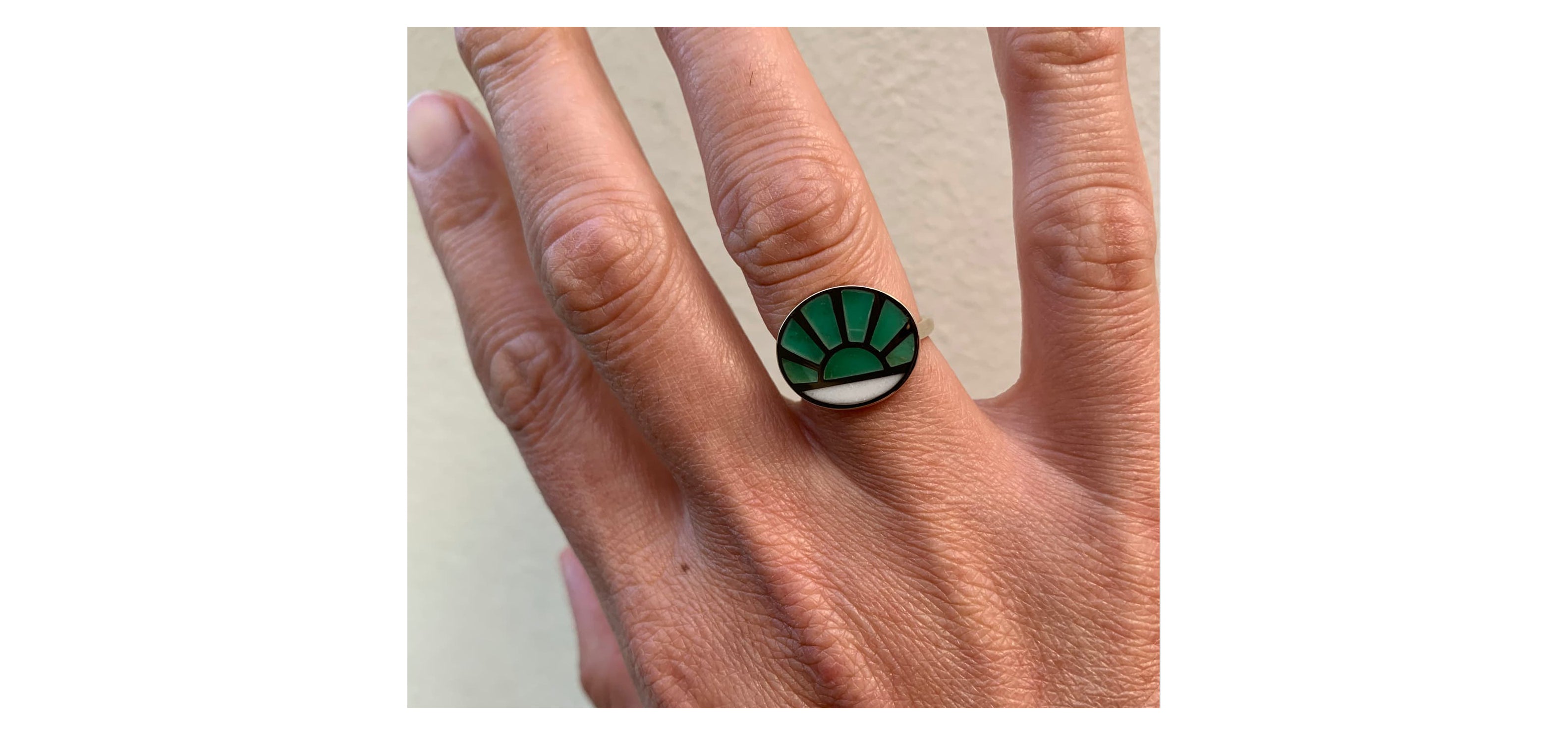 a close up picture of a hand wearing a sun shaped ring