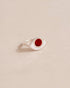 A silver ring with a carnelian stone in the shape of an eye, placed on a neutral background.