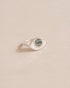 A silver ring with a labradorite stone centered on a white background, resembling an eye talisman design.