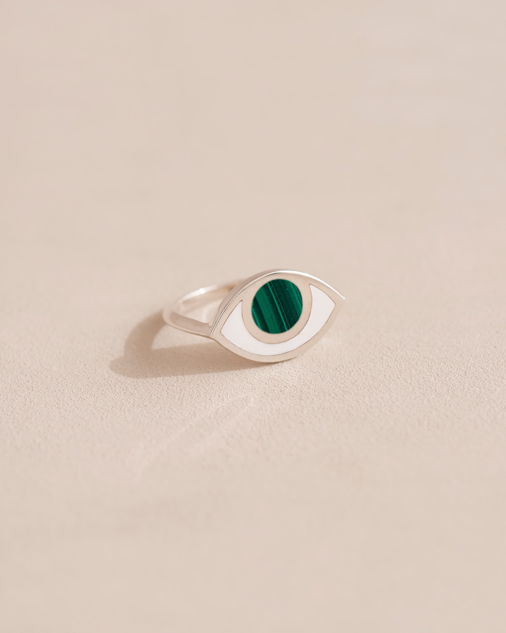 Silver ring with green stone on beige background