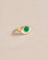 A 14K yellow gold ring with a variscite stone shaped like an eye, placed on a beige background.
