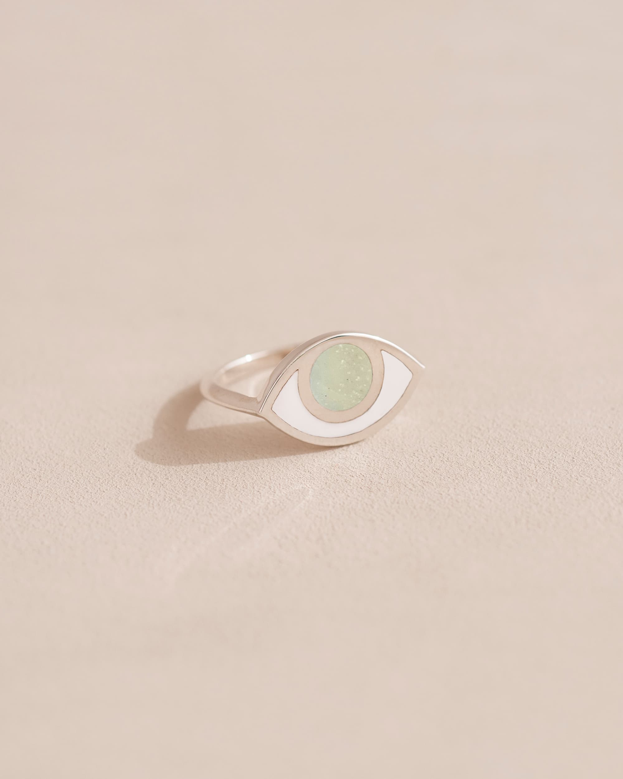 A silver ring with an opal center stone shaped like an eye, placed on a light background.