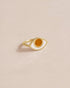 A gold-colored ring with a mookaite stone shaped like an eye on a light background.