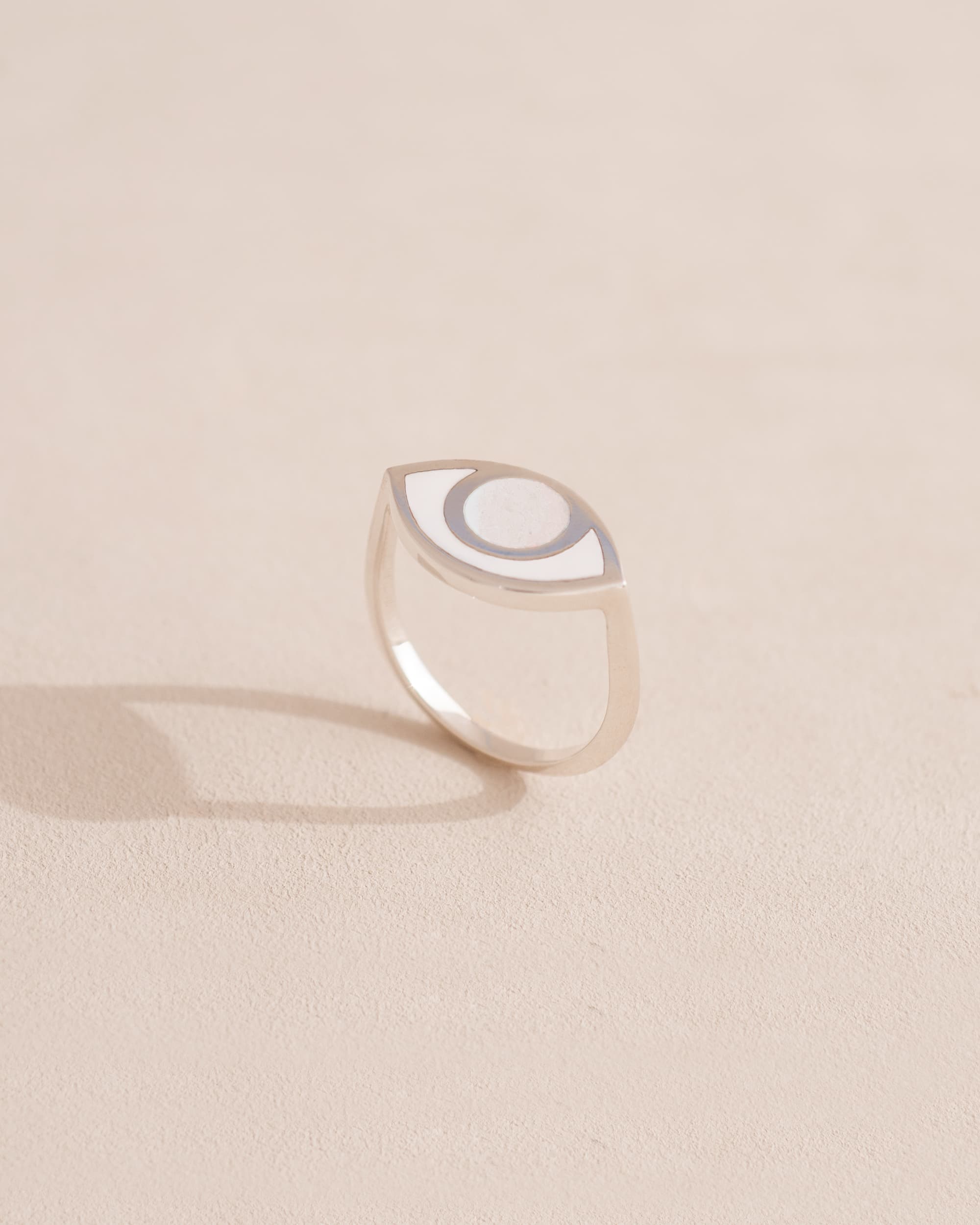 Silver ring with a half-moon design on a beige background