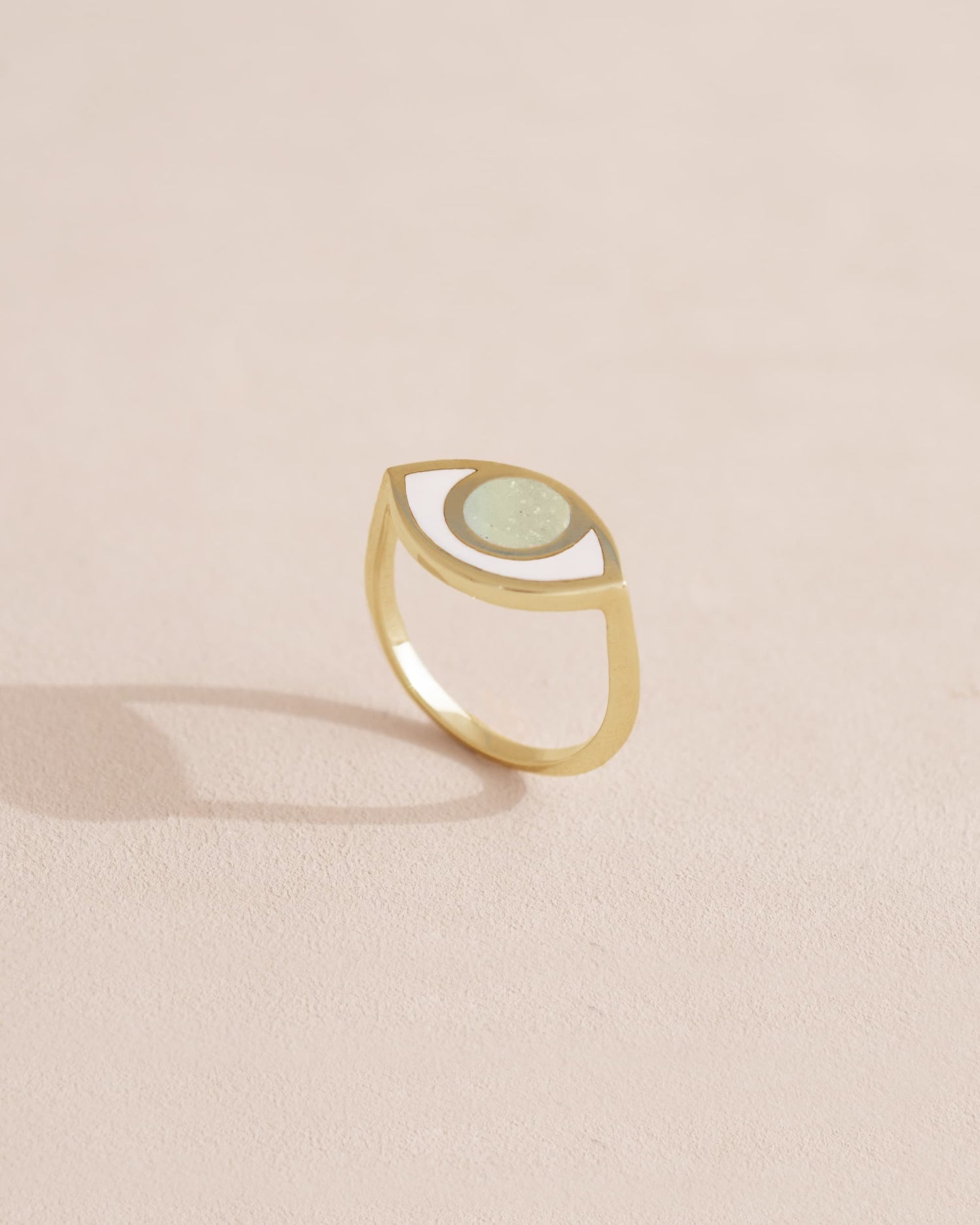 Gold ring with a green stone on a light beige background