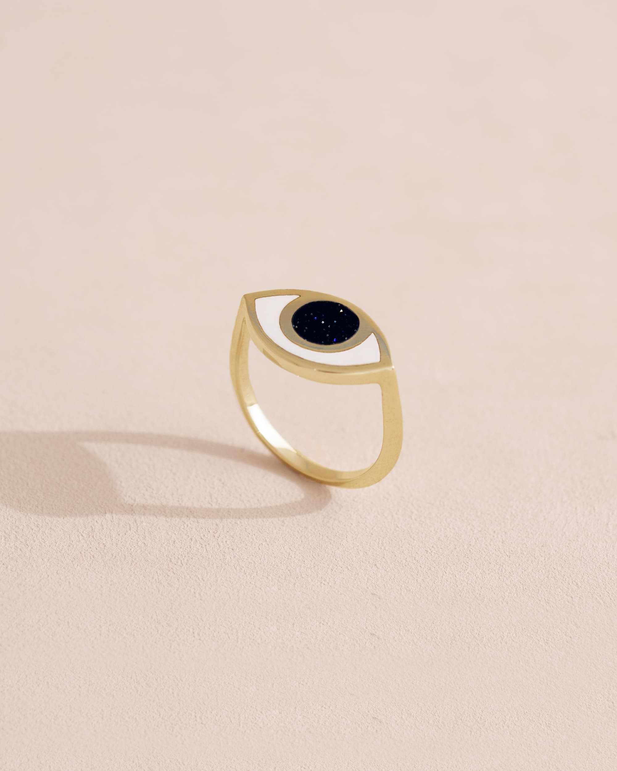 Gold ring with black stone on a light beige background