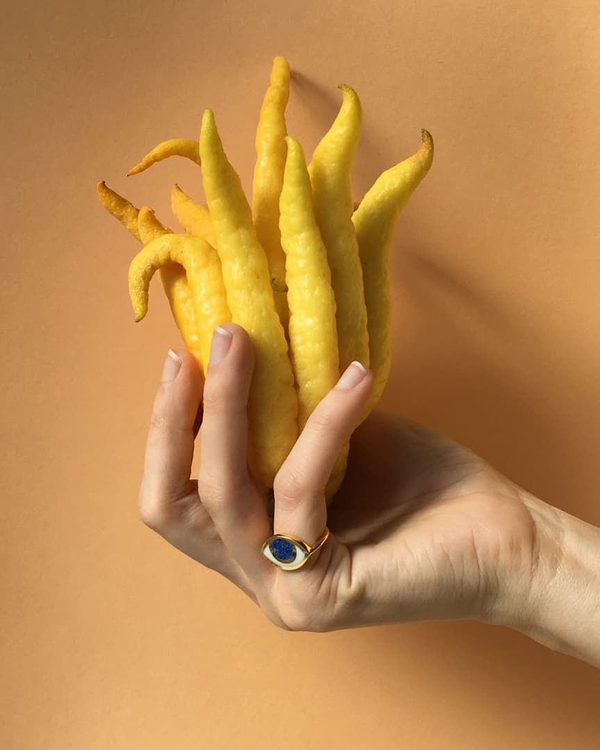 An eye shaped ring worn by a hand holding a buddha&