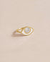 A gold ring with a mother of pearl inlay shaped like an eye, displayed against a light background.