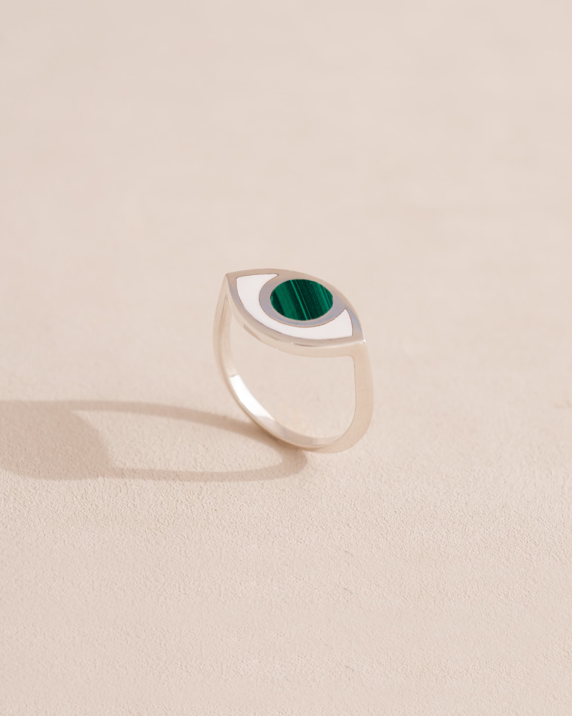 Silver ring with green stone on a neutral background