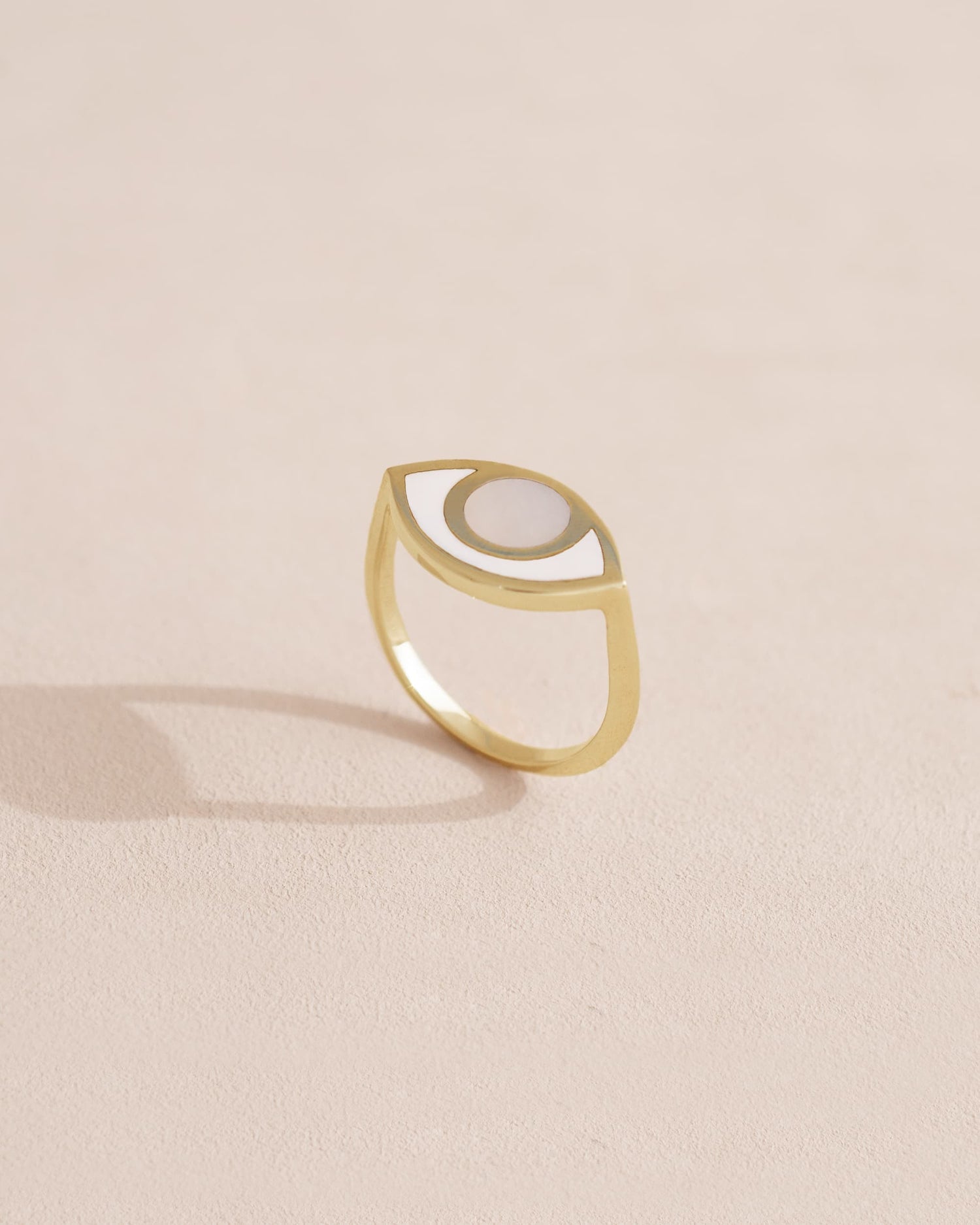 Gold ring with a half-moon design on a light beige background