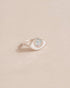 A silver ring shaped like an eye with an opal stone set in the center, on a neutral background.