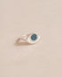 A silver ring shaped like an eye with a dark opal stone set in the center, on a neutral background.