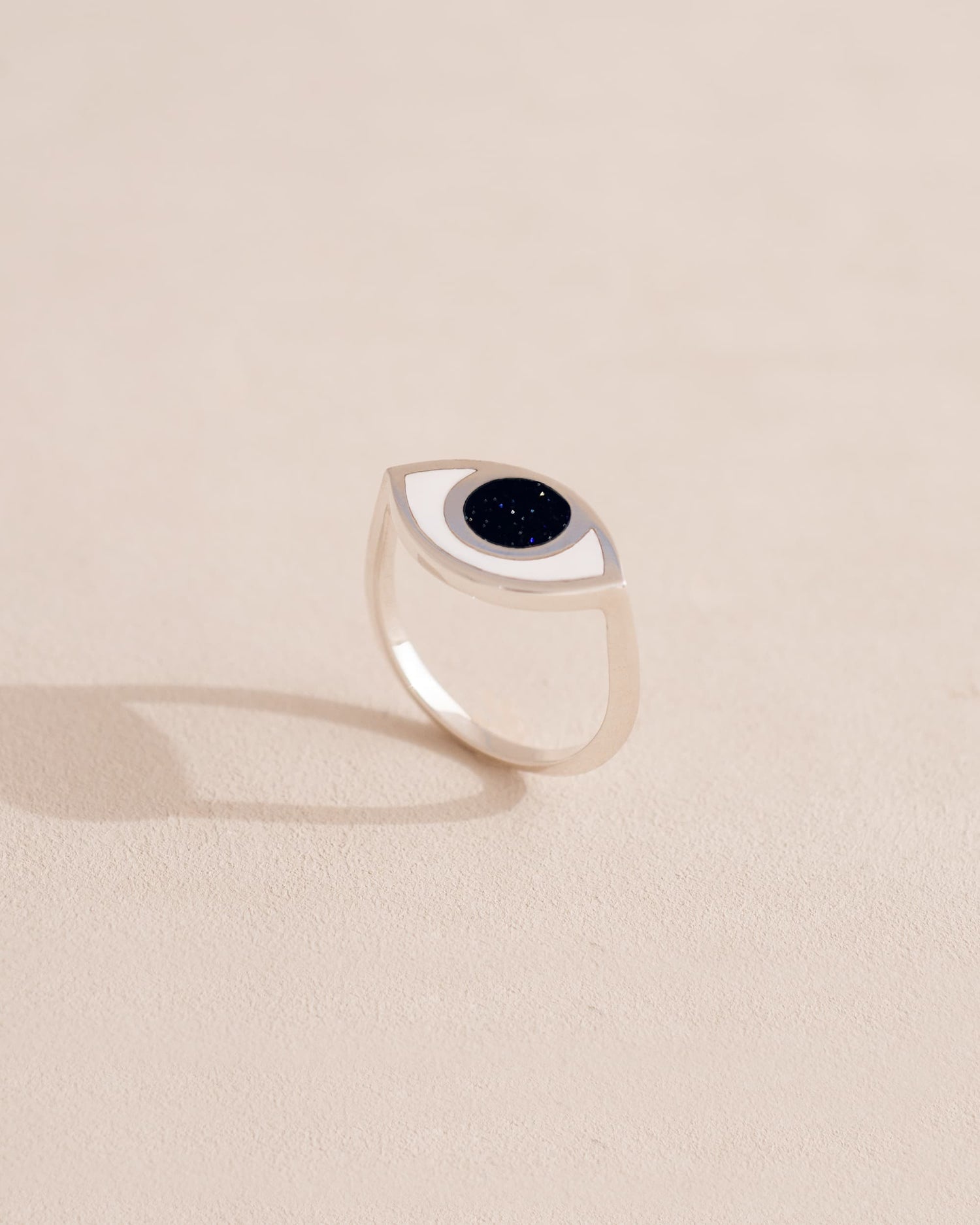Silver ring with black stone on a light beige background