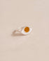 A silver ring with a mookaite stone shaped like an eye, placed on a light background.