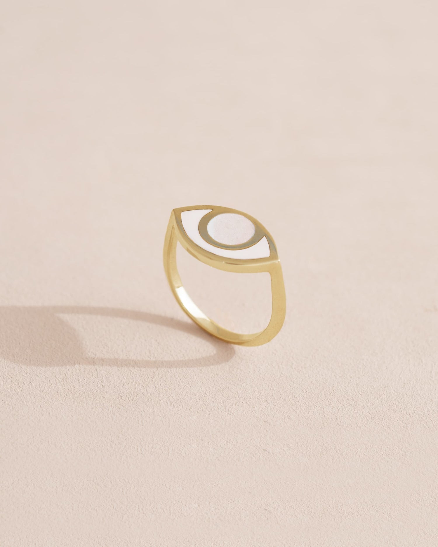 A porcelain ring with a gold band, designed to resemble an eye, placed on a light background.