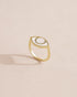 A porcelain ring with a gold band, designed to resemble an eye, placed on a light background.